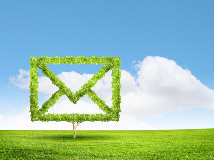 Email concept green outline of email in a green field with blue sky